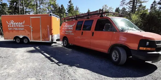 Reese Electric van and matching equipment trailer on a gravel lot
