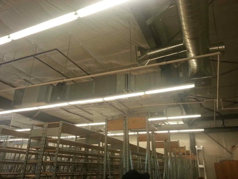 Long rows of new light fixtures hung over open warehouse racking
